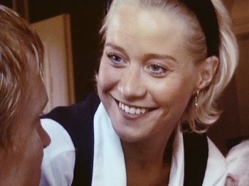 Movie still from “The Celebration” (1998), directed by Thomas Vinterberg – A person wearing a hat and smiling; Close Up shot, Over the shoulder angle