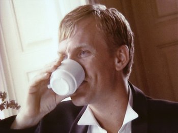 Movie still from “The Celebration” (1998), directed by Thomas Vinterberg – A person drinking a cup of coffee; Close Up shot, Low angle