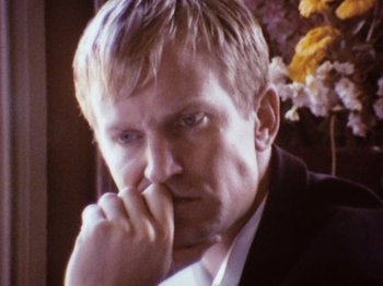 Movie still from “The Celebration” (1998), directed by Thomas Vinterberg – A person wearing a suit and holding his hand to his face; Close Up shot, High angle