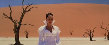 Movie still from “The Cell” (2000), directed by Tarsem Singh – A woman standing in front of a sand dune; Medium shot, Low angle
