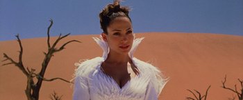 Movie still from “The Cell” (2000), directed by Tarsem Singh – A woman wearing a white dress with feathers around her neck; Close Up shot, Low angle