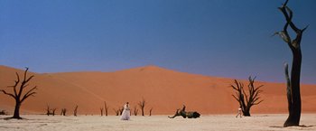 Movie still from “The Cell” (2000), directed by Tarsem Singh – A woman in a white dress standing next to an elephant in the desert; Extreme Wide shot, Low angle