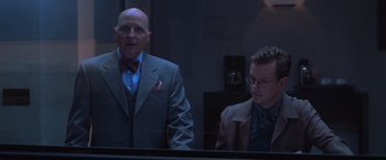 Movie still from “The Cell” (2000), directed by Tarsem Singh – A man and a man standing next to each other in a room; Medium shot, Low angle