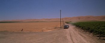 Movie still from “The Cell” (2000), directed by Tarsem Singh – A car driving down a dirt road in the middle of a desert; Extreme Wide shot, High angle