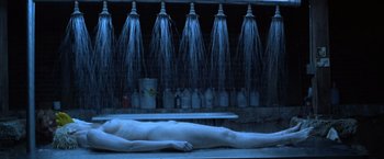 Movie still from “The Cell” (2000), directed by Tarsem Singh – A man laying on the ground in front of a bunch of bottles; Wide shot, High angle