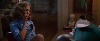 Movie still from “The Cell” (2000), directed by Tarsem Singh – A woman sitting on the floor smoking a cigarette; Medium shot, Over the shoulder angle