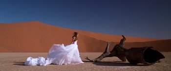 Movie still from “The Cell” (2000), directed by Tarsem Singh – A woman in a white dress and a camel in the desert; Wide shot, Low angle