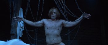 Movie still from “The Cell” (2000), directed by Tarsem Singh – A shirtless man chained up in a dark room; Medium shot, High angle