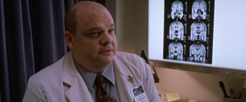 Movie still from “The Cell” (2000), directed by Tarsem Singh – A man in a white lab coat with a badge on his chest; Close Up shot, Low angle