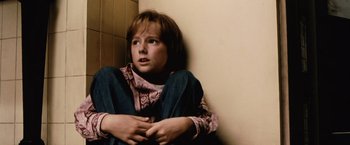 Movie still from “The Cell” (2000), directed by Tarsem Singh – A young boy sitting against a wall with his arms crossed; Close Up shot, High angle