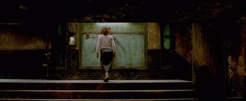 Movie still from “The Cell” (2000), directed by Tarsem Singh – A woman walking down the steps in front of a wall; Wide shot, Low angle