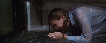 Movie still from “The Cell” (2000), directed by Tarsem Singh – A woman with wet hair leaning on a wall; Medium shot, High angle