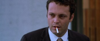 Movie still from “The Cell” (2000), directed by Tarsem Singh – A person wearing a suit smoking a cigarette; Close Up shot, Low angle