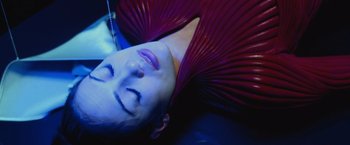 Movie still from “The Cell” (2000), directed by Tarsem Singh – A woman laying on top of a bed in a room; Close Up shot, Overhead angle