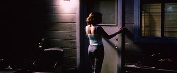 Movie still from “The Cell” (2000), directed by Tarsem Singh – A woman standing in front of a door in the dark; Medium shot, Over the shoulder angle
