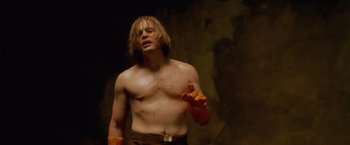 Movie still from “The Cell” (2000), directed by Tarsem Singh – A shirtless man in a black shirt and orange gloves; Medium shot, Low angle