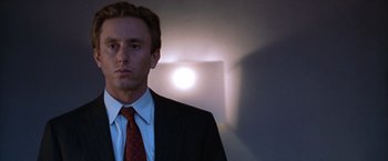 Movie still from “The Cell” (2000), directed by Tarsem Singh – A man wearing a suit and tie standing in front of a wall; Close Up shot, Low angle