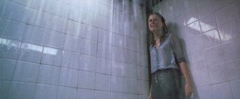 Movie still from “The Cell” (2000), directed by Tarsem Singh – A woman standing next to a tiled wall in a bathroom; Medium shot, Low angle