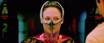 Movie still from “The Cell” (2000), directed by Tarsem Singh – A woman wearing a red and black outfit with a metal mask on her face; Close Up shot, Low angle