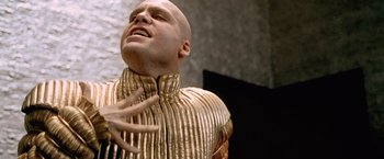 Movie still from “The Cell” (2000), directed by Tarsem Singh – A bald man in a gold suit is looking up; Close Up shot, Low angle