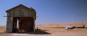 Movie still from “The Cell” (2000), directed by Tarsem Singh – A man sitting in front of an abandoned building; Extreme Wide shot, Low angle