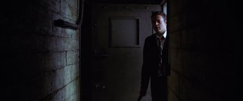 Movie still from “The Cell” (2000), directed by Tarsem Singh – A man in a suit and tie holding a gun; Medium shot, Low angle