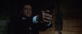 Movie still from “The Cell” (2000), directed by Tarsem Singh – A man in a suit and tie holding a gun; Close Up shot, Low angle