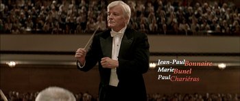 Movie still from “The Chorus” (2004), directed by Christophe Barratier – A man in a tuxedo holding a conductor's baton in front of an audience; Close Up shot, Low angle