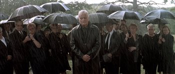 Movie still from “The Chorus” (2004), directed by Christophe Barratier – A group of people standing in the rain holding umbrellas; Wide shot, High angle