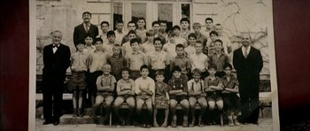Movie still from “The Chorus” (2004), directed by Christophe Barratier – An old photo of a group of boys sitting in front of a building; Wide shot, High angle