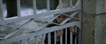 Movie still from “The Chorus” (2004), directed by Christophe Barratier – A young boy looking through the bars of an iron fence; Close Up shot, High angle