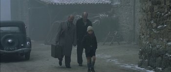 Movie still from “The Chorus” (2004), directed by Christophe Barratier – A group of people walking on a dirt road; Wide shot, Over the shoulder angle
