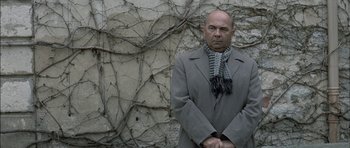 Movie still from “The Chorus” (2004), directed by Christophe Barratier – A bald man in a gray coat and a scarf; Medium shot, Low angle