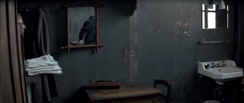 Movie still from “The Chorus” (2004), directed by Christophe Barratier – A wooden table and chair in a room with a mirror on the wall; Wide shot, High angle