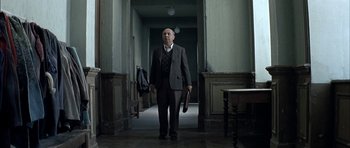 Movie still from “The Chorus” (2004), directed by Christophe Barratier – A man in a suit holding a briefcase in a hallway; Wide shot, Low angle