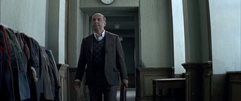 Movie still from “The Chorus” (2004), directed by Christophe Barratier – A man in a suit and tie holding a briefcase in a hallway; Medium shot, Low angle