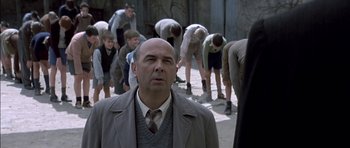 Movie still from “The Chorus” (2004), directed by Christophe Barratier – A man standing in front of a group of people; Medium shot, Over the shoulder angle
