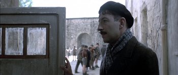 Movie still from “The Chorus” (2004), directed by Christophe Barratier – A group of people standing around a building; Close Up shot, Over the shoulder angle