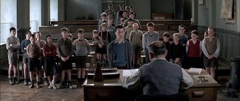 Movie still from “The Chorus” (2004), directed by Christophe Barratier – A group of young men standing in front of a piano; Medium shot, Over the shoulder angle