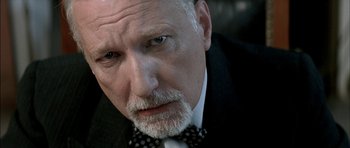 Movie still from “The Chorus” (2004), directed by Christophe Barratier – An older man with a beard wearing a suit and bow tie; Close Up shot, Low angle