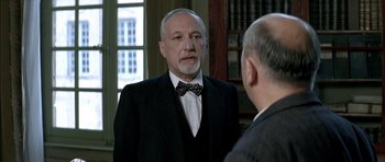 Movie still from “The Chorus” (2004), directed by Christophe Barratier – An older man wearing a suit and a bow tie; Close Up shot, Over the shoulder angle