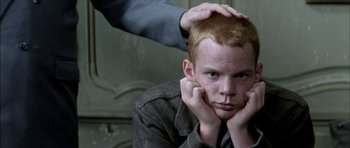 Movie still from “The Chorus” (2004), directed by Christophe Barratier – A young boy with a red head is sitting in front of a man; Close Up shot, Over the shoulder angle