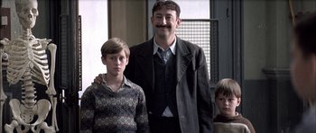 Movie still from “The Chorus” (2004), directed by Christophe Barratier – A man and two young boys standing next to each other; Medium shot, Low angle