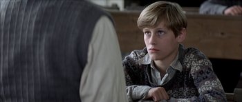 Movie still from “The Chorus” (2004), directed by Christophe Barratier – A young boy sitting in front of another person; Close Up shot, Over the shoulder angle