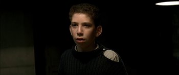 Movie still from “The Chorus” (2004), directed by Christophe Barratier – A young man wearing a black sweater and a white shirt; Close Up shot, High angle
