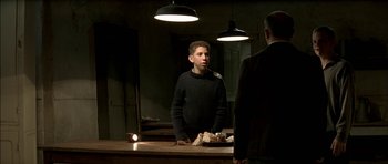 Movie still from “The Chorus” (2004), directed by Christophe Barratier – A young man standing in front of a man in a suit in front of a mirror; Medium shot, Over the shoulder angle