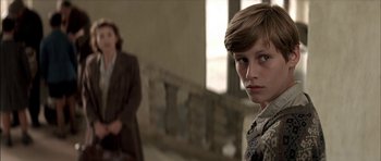 Movie still from “The Chorus” (2004), directed by Christophe Barratier – A young boy standing in front of a woman; Close Up shot, Over the shoulder angle