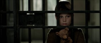 Movie still from “The Chorus” (2004), directed by Christophe Barratier – A boy holding a teddy bear behind a fence; Close Up shot, Low angle