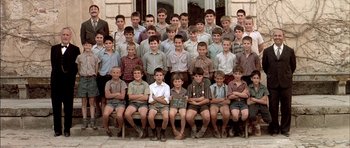 Movie still from “The Chorus” (2004), directed by Christophe Barratier – A group of young men sitting on top of a wooden bench; Wide shot, High angle