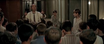 Movie still from “The Chorus” (2004), directed by Christophe Barratier – A group of people sitting in front of a group of kids; Medium shot, High angle